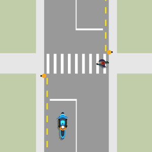 A blue motorcycle is stopped behind a white line in front of a pedestrian crossing. A pedestrian is crossing the road.