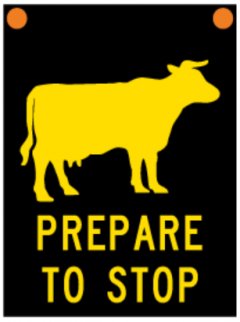 Sign which says prepare to stop below of a cow symbol and it has active flashing light