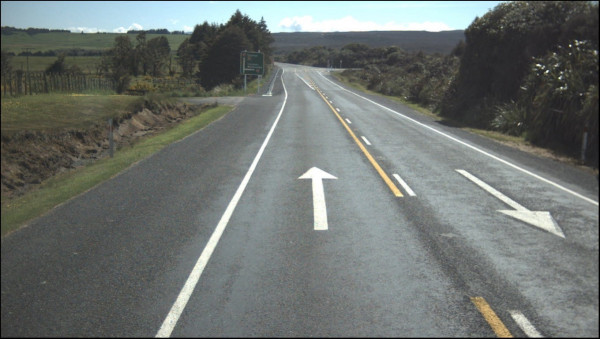 Image which shows an intersection with white arrow marked as a reminder to keep left