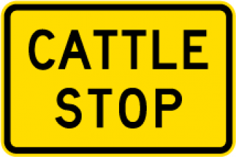 Warning sign which says cattle stop on yellow rectangular background