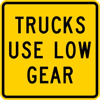 Traffic sign which says trucks use low gear on a yellow background