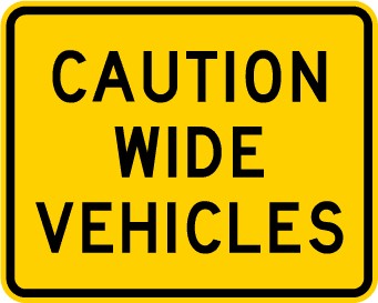 Traffic sign which says caution wide vehicles on yellow rectangular background 