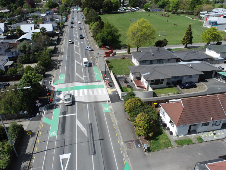 Photo from a birds eye view showing cars travelling along a road with a raised pedestrian crossing