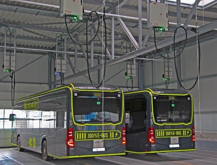 Buses being charged by overhead chargers