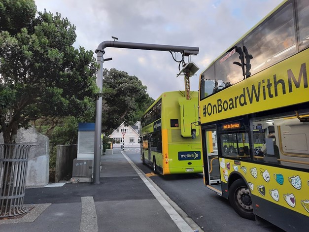 A bottom-up pantograph charger connected to double deck bus in Wellington at a bus stop.