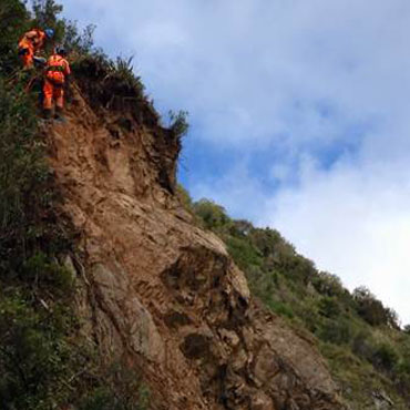 Abseilers work to remove rock from the hillside. 