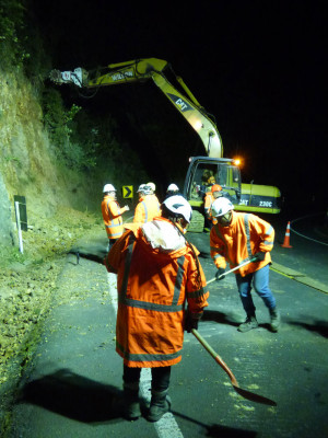 The milling machine in action on the Brynderwyn Hills on SH1 with workers clearing the dislodged rocks from the road.