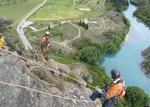 Two abseilers above the Kawarau River, removing loose rocks on the Nevis Bluff in past scaling seasons.