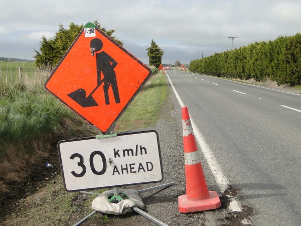 30km/h ahead road works sign and road cone on the left side of a rural road