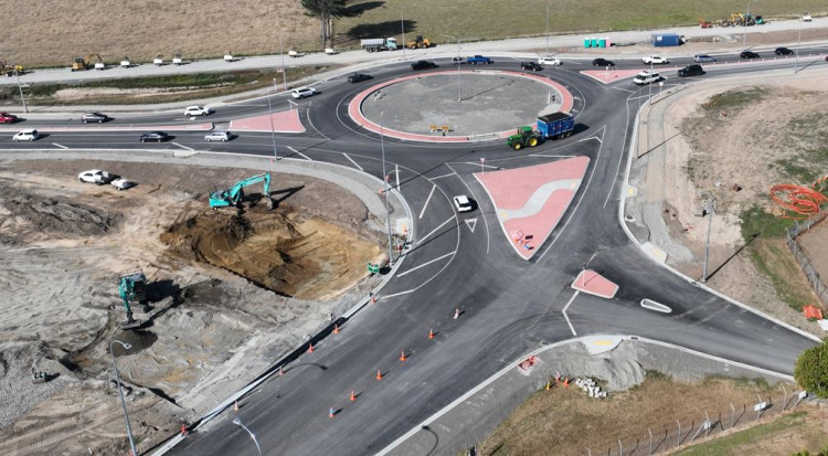 Aerial shot of a road intersection with construction vehicles by a roundabout.