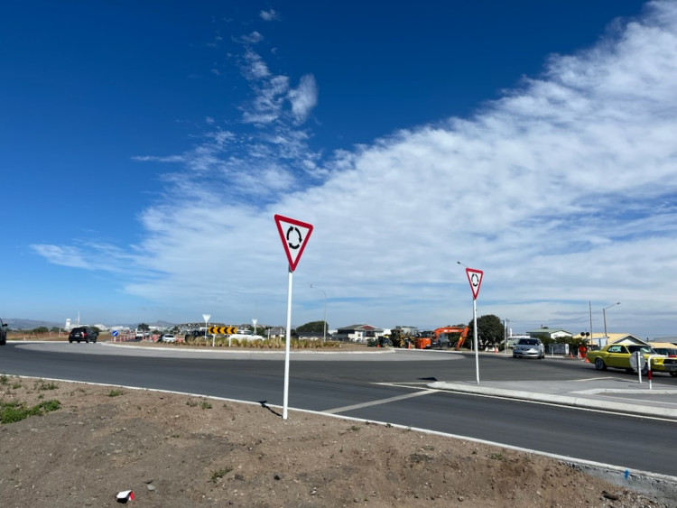 A road with a traffic light and a sign indicating roundabout directions.