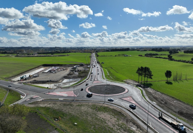 An aerial view of a road construction site with moving traffic around the roundabout.