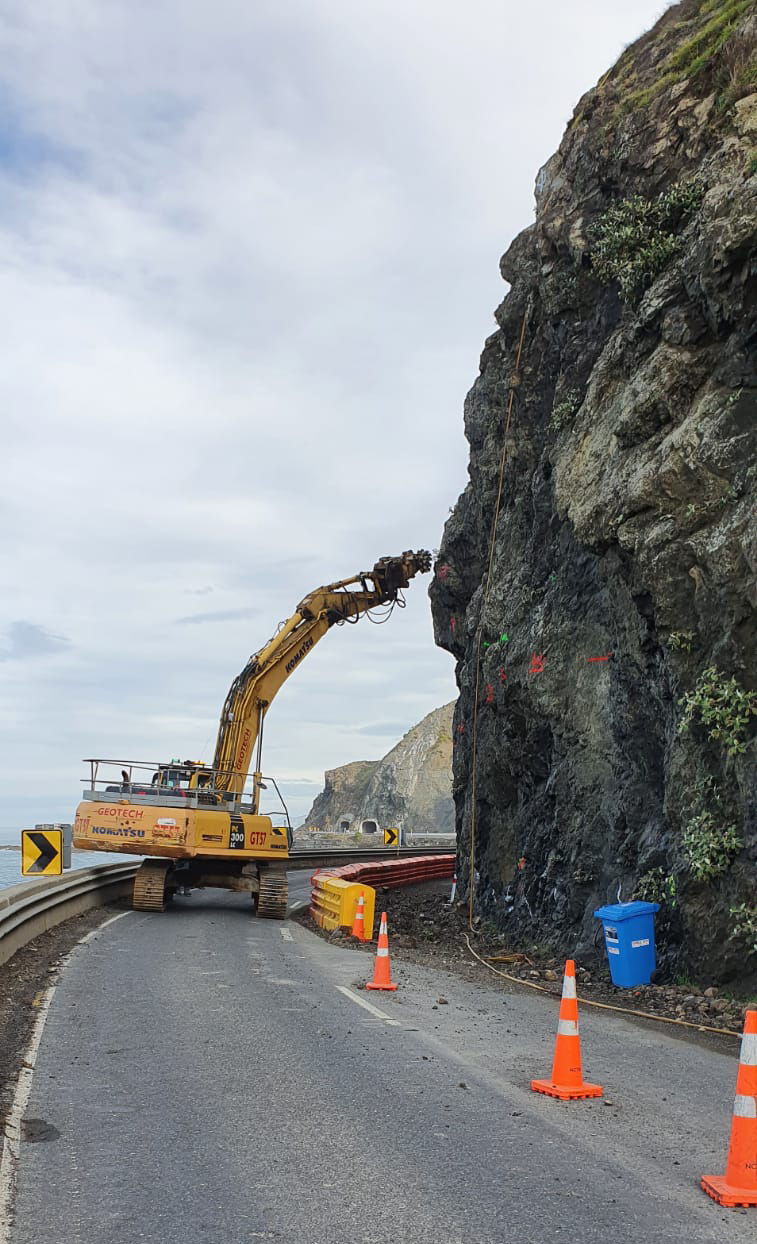 Machine grinding the rock edge with road cones in the foreground