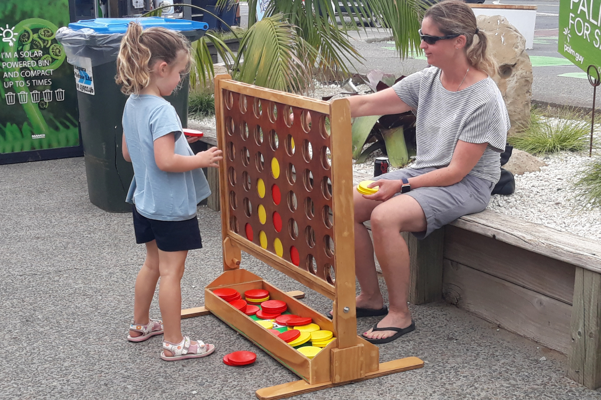 Mother and daughter playing outside with a giant Connect Four game