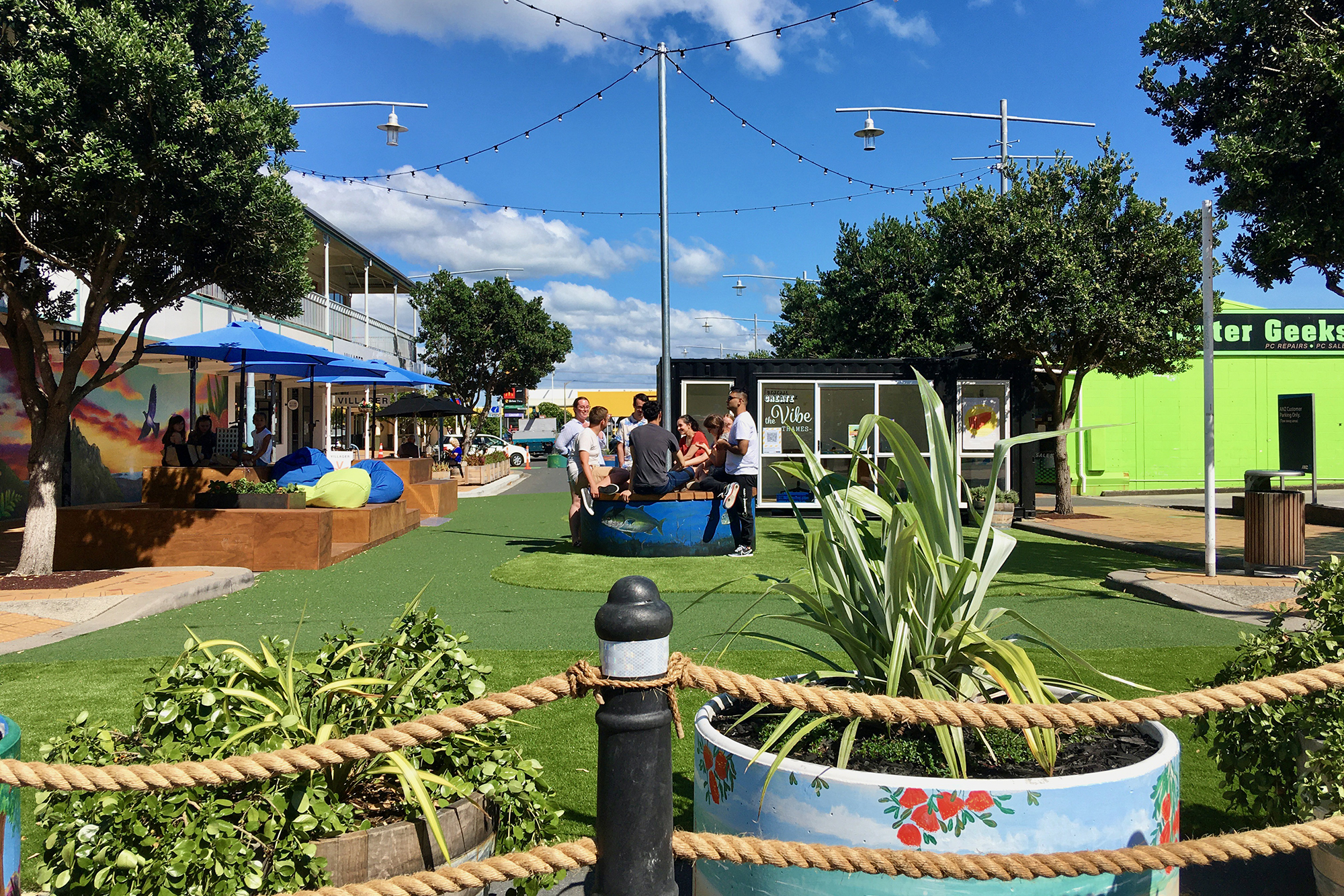 Artificial turf with bean bags, festive string lights and people gathered in the middle.