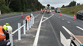 road workers installing median barriers on a highway