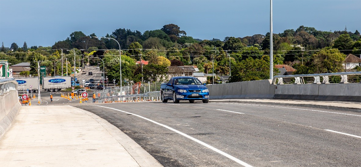 Blue car driving over the new Rāhui Road Bridge.