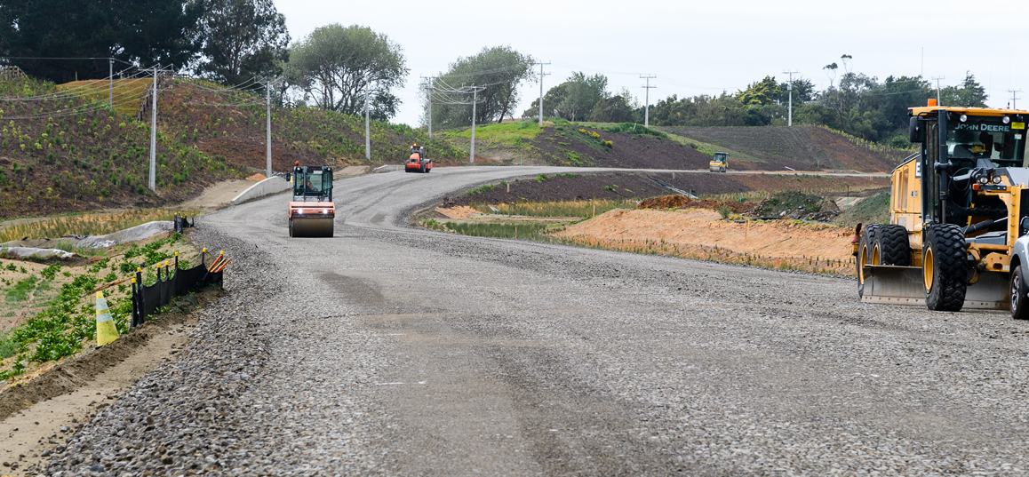 Earthworks machine compacting seal on new local arterial road.