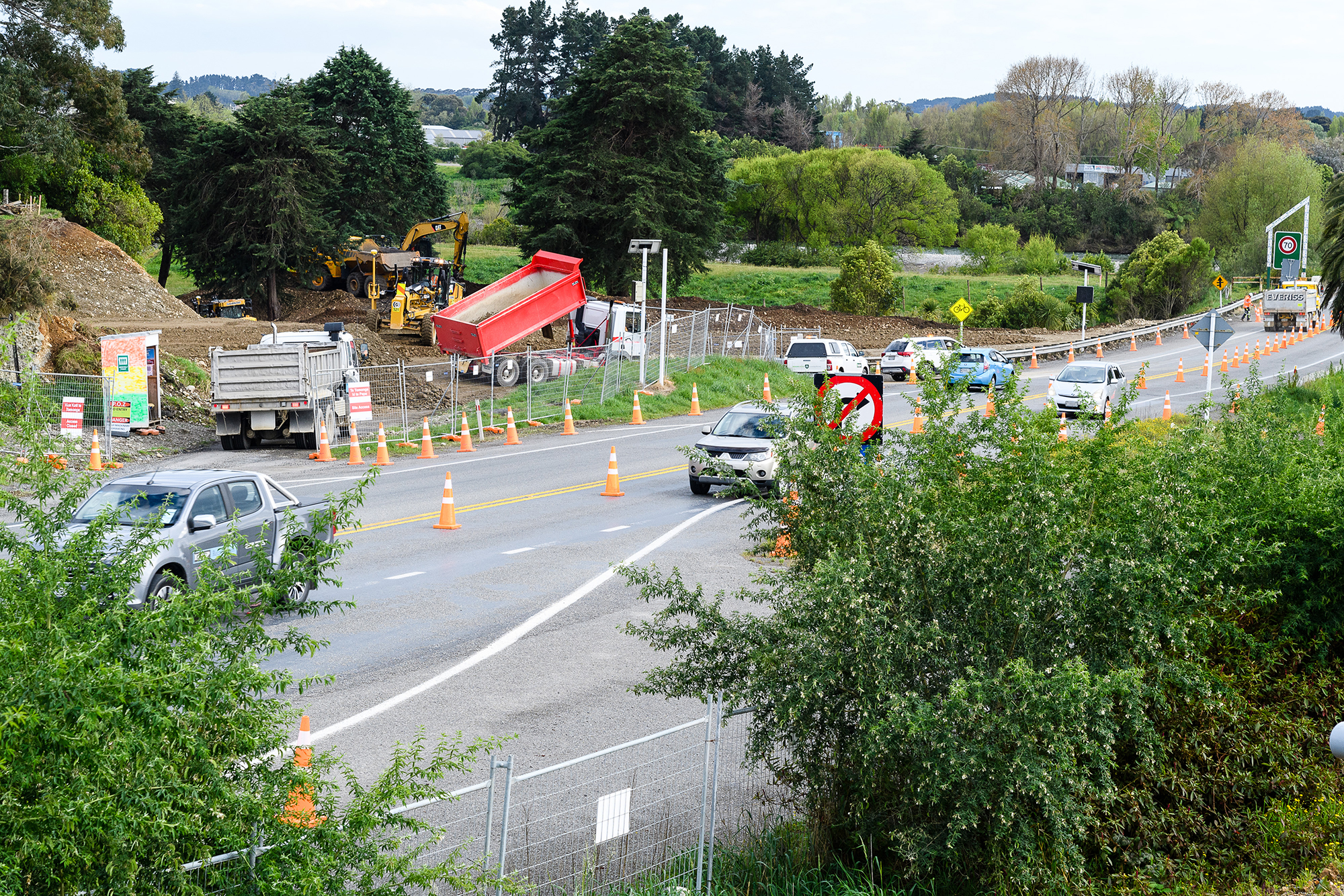 Trucks moving dirt while cars drive past on the south end of the current Ōtaki River Bridge.