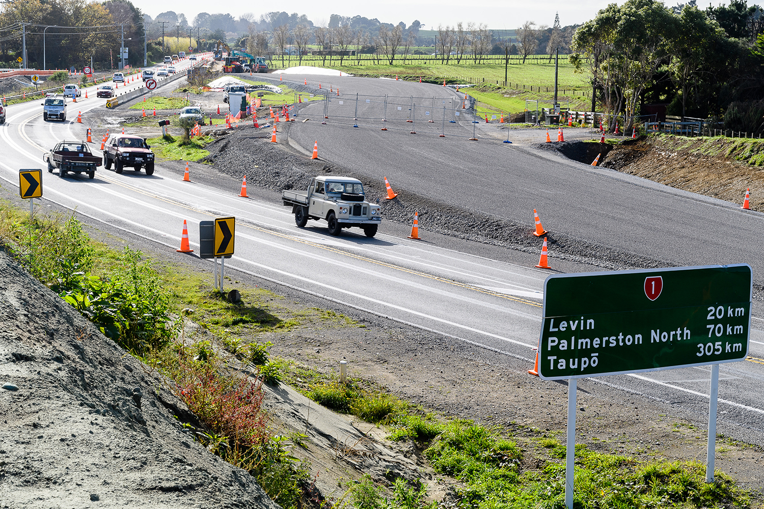 Vehicles on current SH1 with new expressway alongside ready for paving.