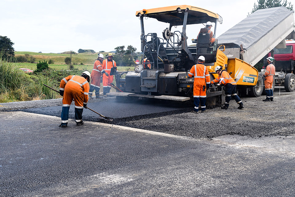 Workers laying out fresh asphalt with machine