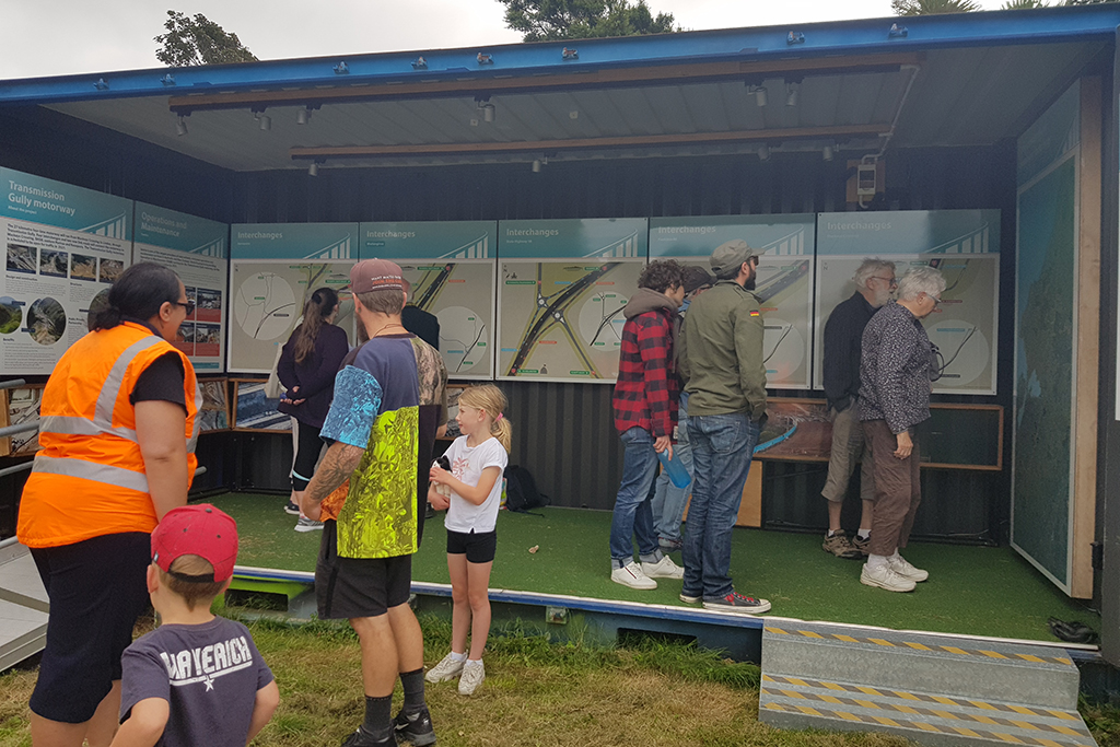 People standing inside and outside the mobile Transmission Gully mobile information centre looking at the maps and information boards. 