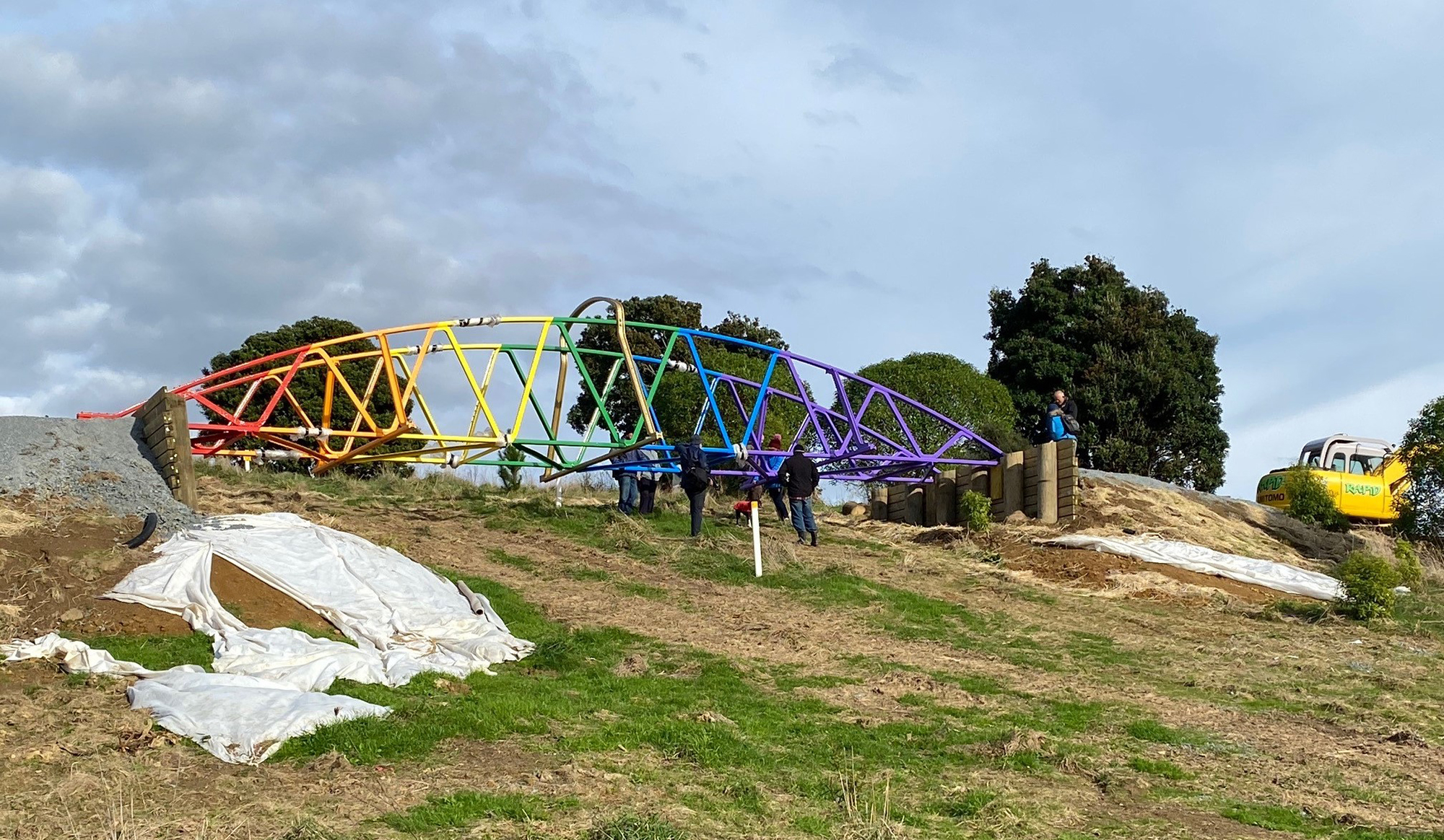 Rainbow bridge being placed in position on hillside.
