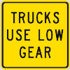 Permanent warning traffic sign says trucks use low gear and the text is on a yellow background