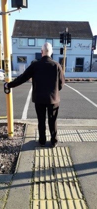 man waiting near the tactile indicator pavement at traffic signals