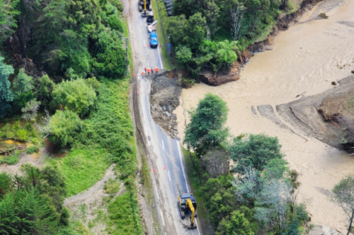 A road with a large portion washed away by a flooded river