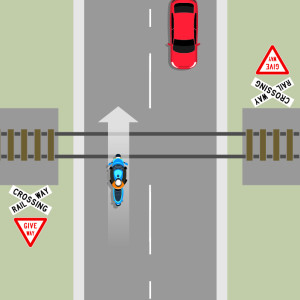 A blue motorcycle crossing railway lines at a 90 degree angle