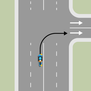 A blue motorcycle is turning right into a one-way street. They must stay in the lane through the intersection.