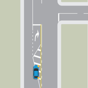 Blue car indicating turning right and moving into a right turn bay with median strip and right turn arrow road marking.