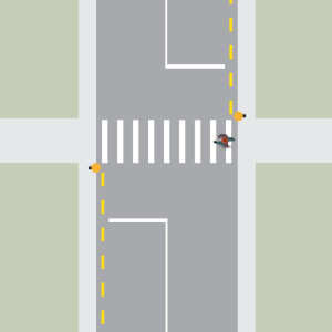 A person is crossing the road from right to left, using a pedestrian crossing without a raised island.