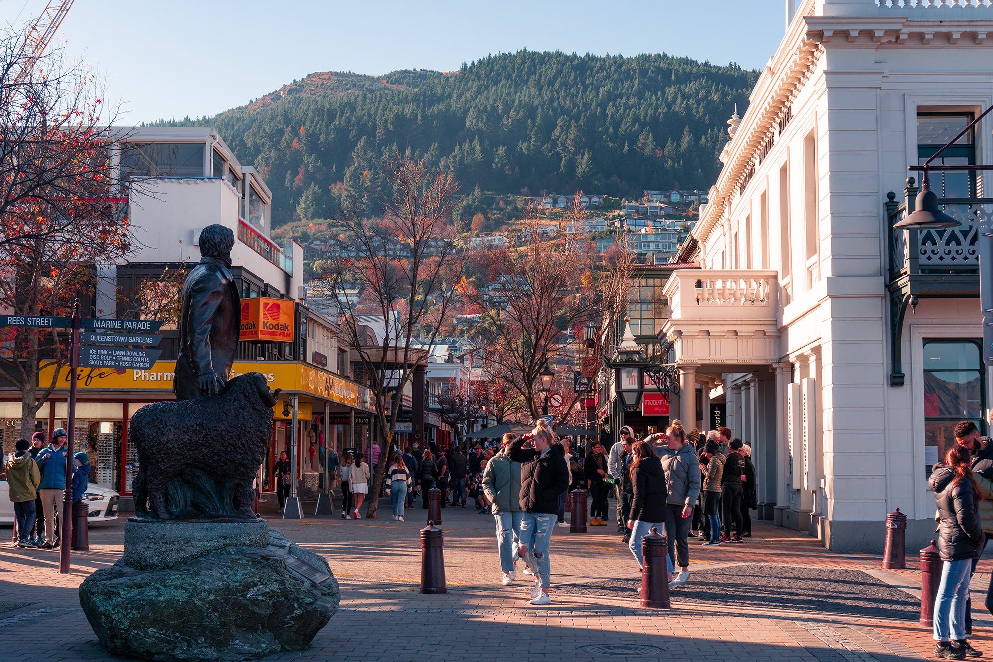 Crowded pedestrianised street with statue in front