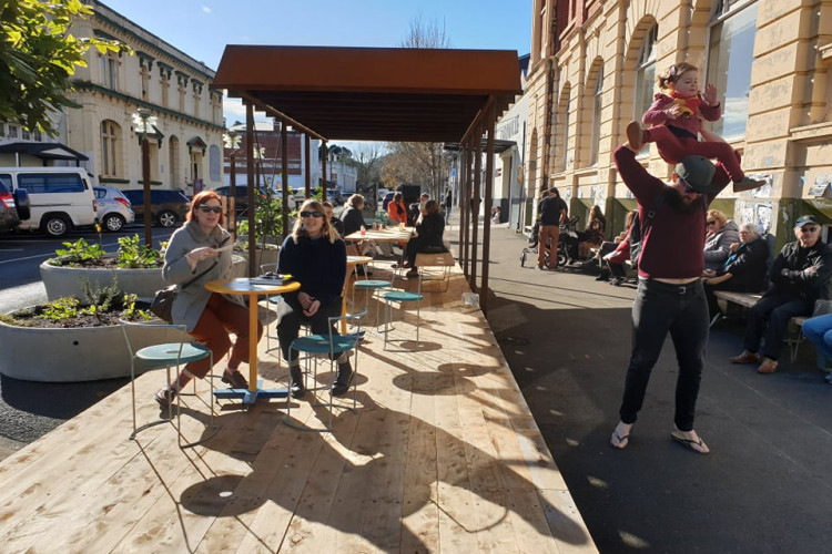 People socialising using public furniture installed in parklet 