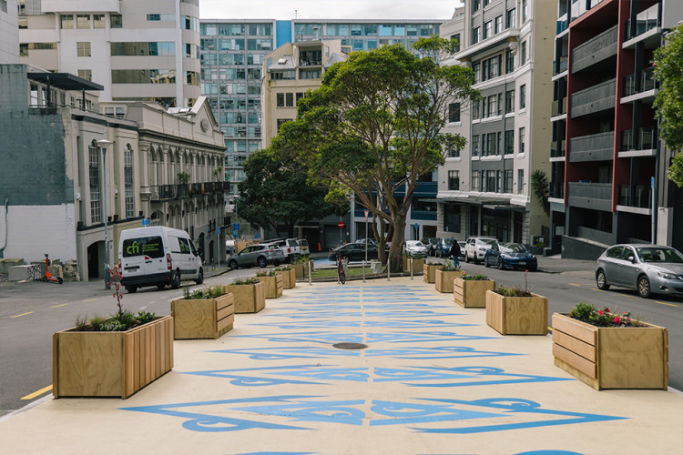 New pedestrian plaza featuring road art and wooden planter boxes on a street