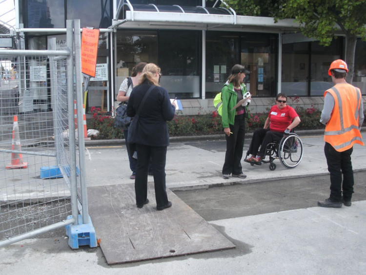 Person with wheelchair through a construction site thoroughfare
