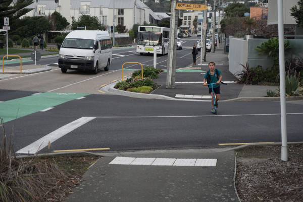a photo showing a child on a scooter crossing a side road between two typical kerb crossing ramps
