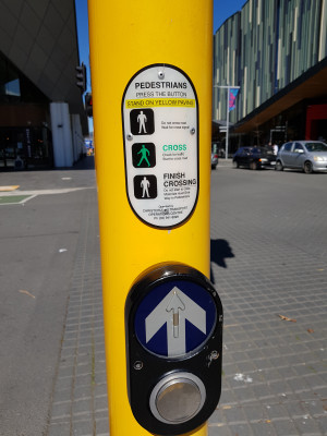 a photo showing a pedestrian push button with explanatory placard