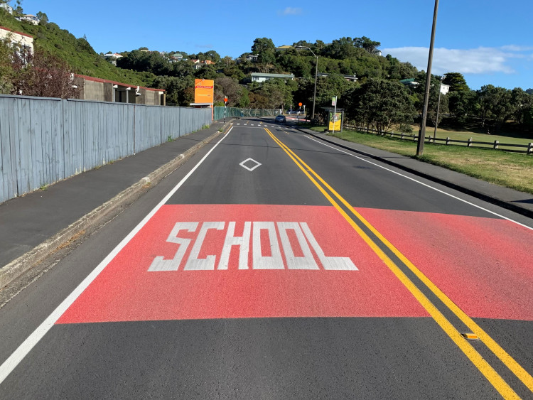 a photo showing a zebra crossing that is operated with a school patrol and advance SCHOOL marking on red block of pavement colour