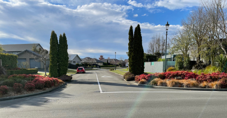 Landscape bushes frame a suburban side street entrance