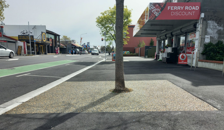 A tree is built into the footpath by covering the soil with rubberised mulch paving to make it flush.