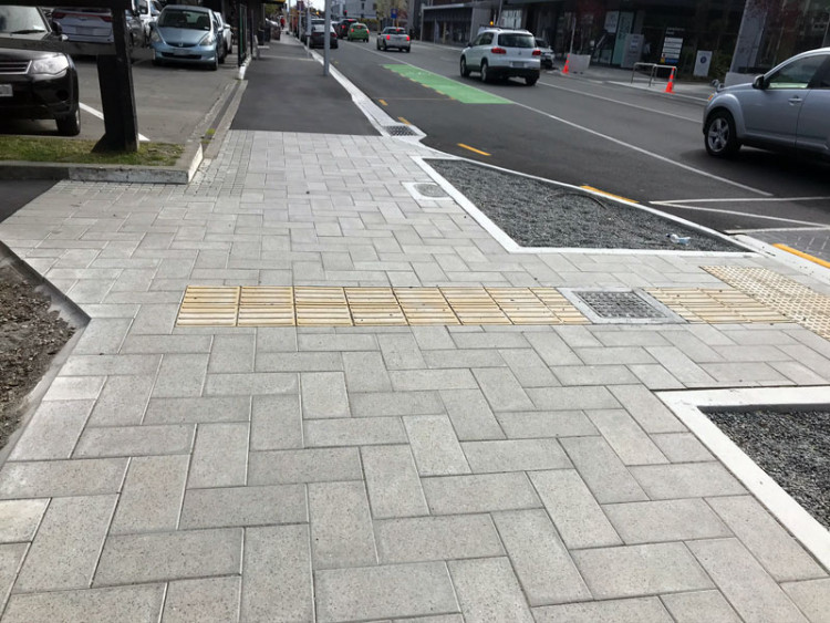 Footpath at street crossing showing directional tiles with patterned modules