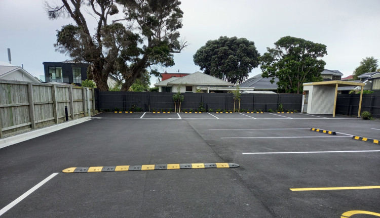 A judder bar in a parking lot with black lines and yellow markings to regulate vehicle speeds.