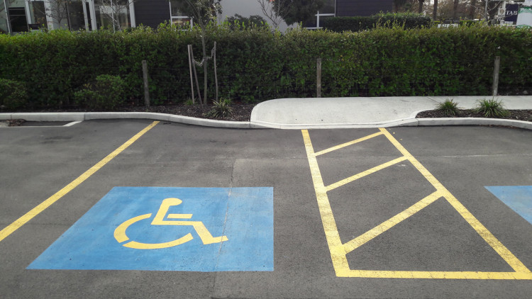 A parking space with a blue and yellow handicap sign, showcasing a good example of an accessible parking space.