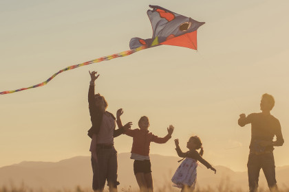A family (two adults and two children) flying a kite
