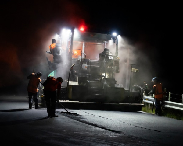 Road workers working at night, laying new asphalt