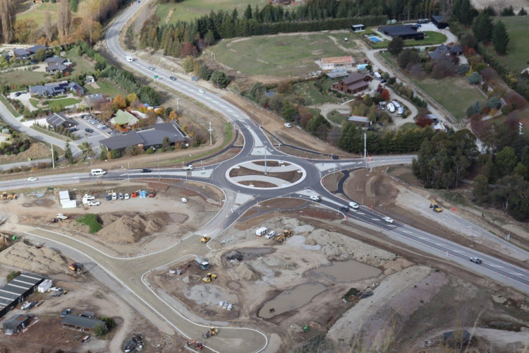 Aerial view of a roundabout intersection, showing cars and traffic moving about.