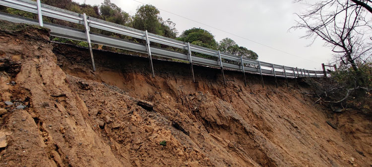 A bridge on the side of a hill with an underslip due to erosion and heavy rainfall.